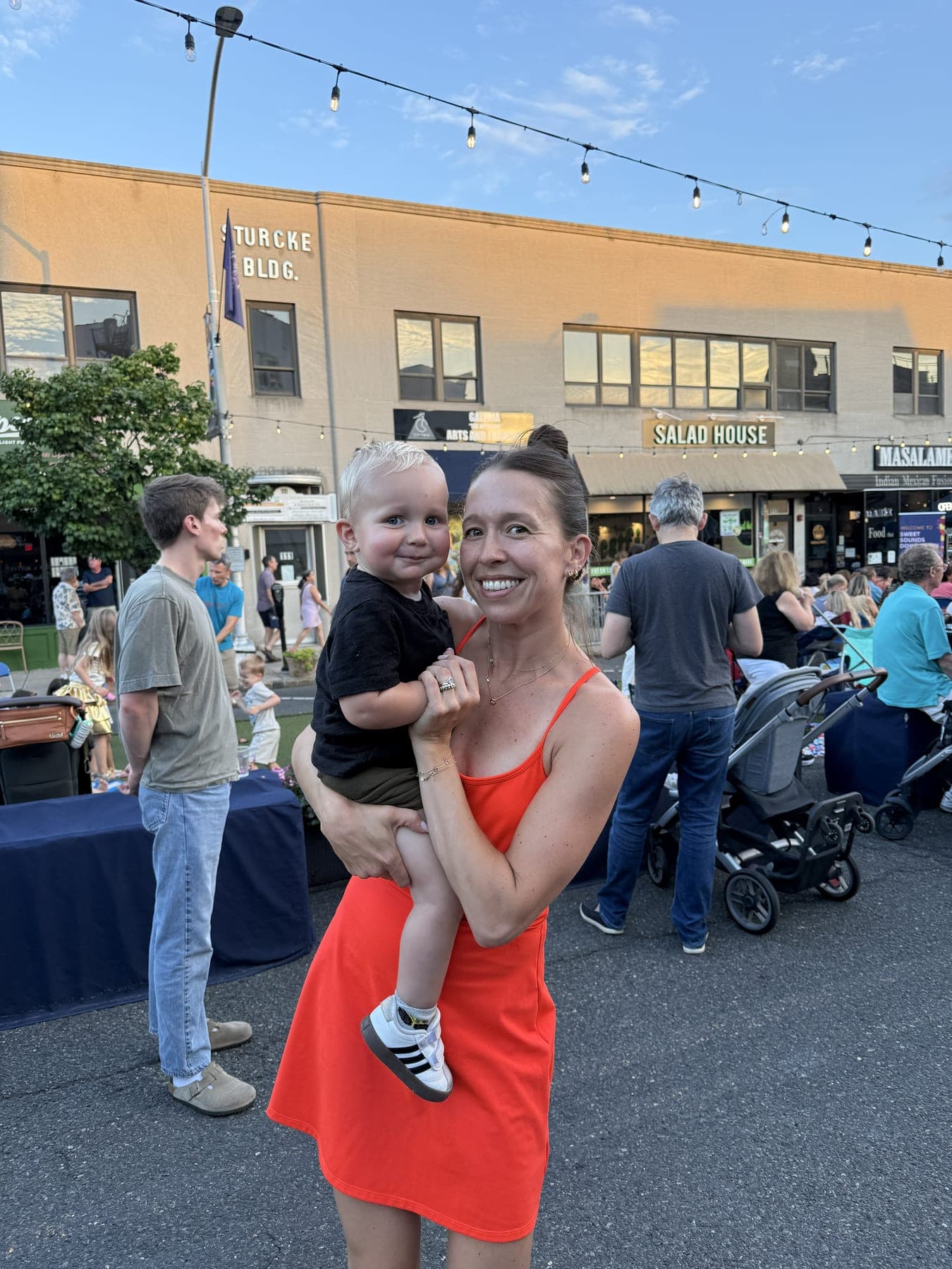 A mother holds her son as families take in the music along Quimby Street's storefronts.