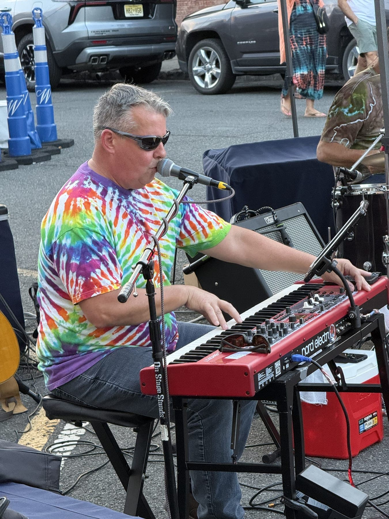A group in tie-dye poses near the stage tent as Scarlet Magnolia performs behind them.