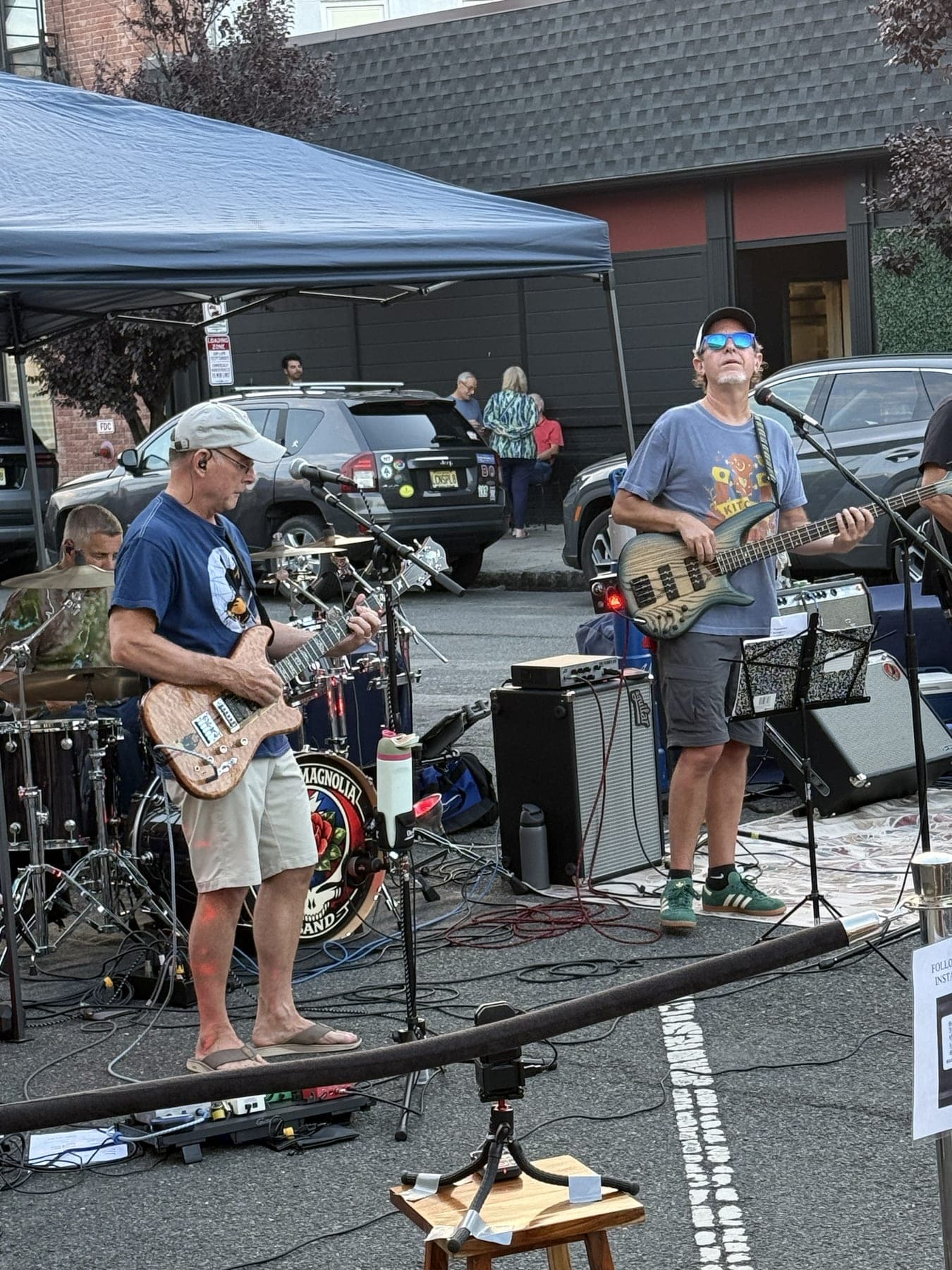 Scarlet Magnolia guitarists perform on Quimby Street beneath the band's Grateful Dead-styled bass drum head.