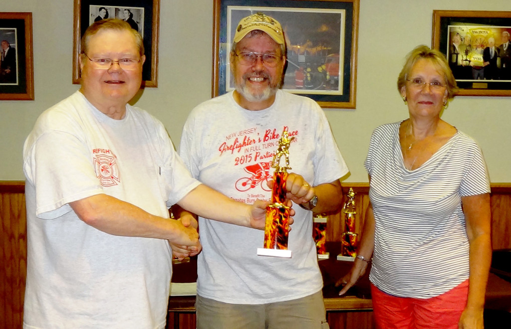 Green Brook Fire EMS racer Ken Larson is presented with the oldest firefighter bicycle racer trophy by race chairman Frank Reilly and Burn Center Foundation director Kathy Conlon.