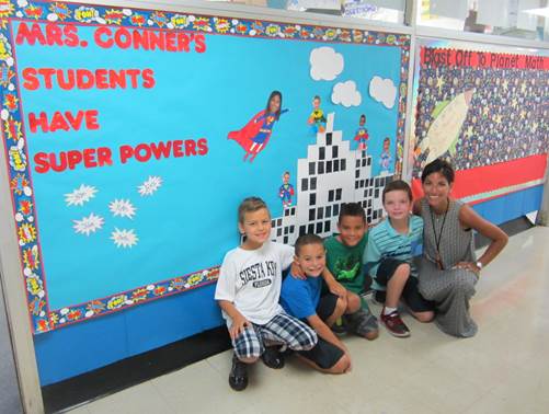 (above) John Ranski, Alex Domingues, Seth Vazquez, and Mrs. Nina Conner posing in front of their superhero bulletin board.