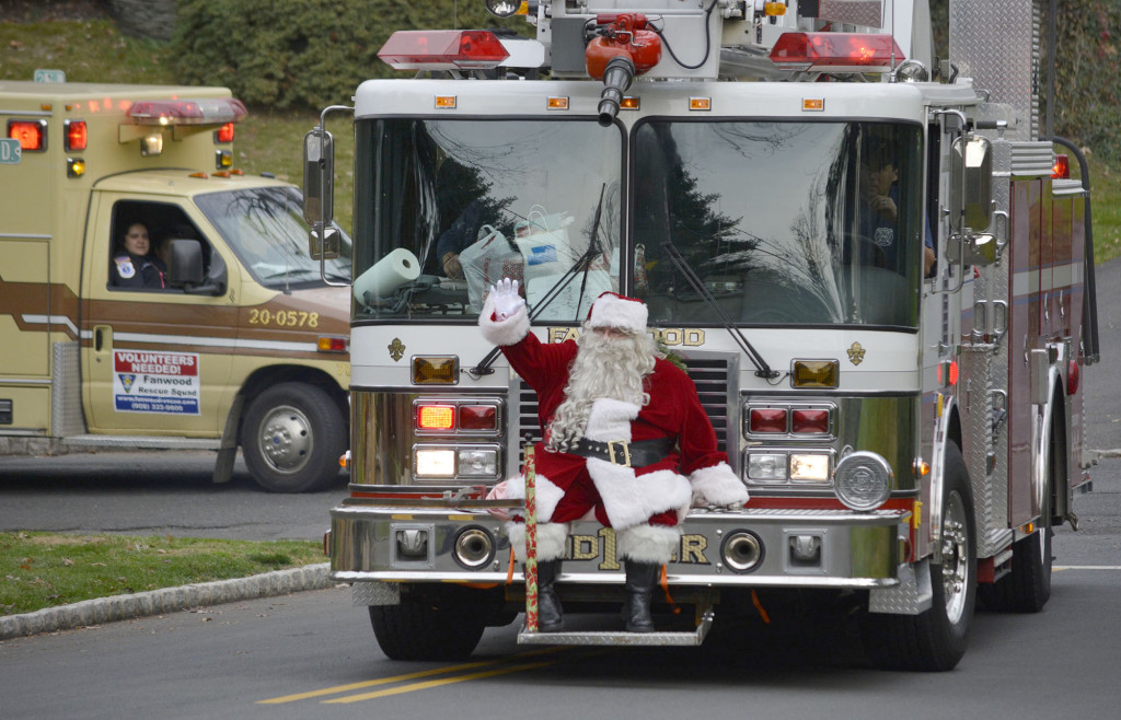 (above) Riding aboard the Fanwood Fire Department’s Ladder One, and accompanied by the Rescue Squad, Santa turns down a street to deliver presents.