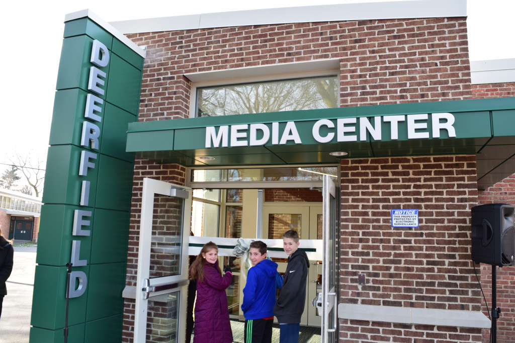 (above l-r), 6th grader Madison Duca, 7th grader Ethan Proper, and 8th grader J.J. Post cutting the ribbon for the official opening of the Deerfield Media Center.