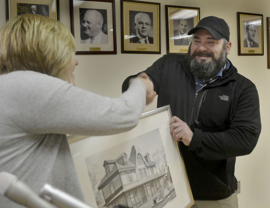 Fanwood Historic Preservation Commission chairman Adam Kois, right, accepts a handshake and a framed print of the borough's historic north side train station from Mayor Colleen Mahr at a borough council meeting in Fanwood, NJ, Tuesday, Feb. 16, 2016. Kois was recognized as the borough's volunteer of the month by the Mayor and Council. (Photo by Brian Horton)