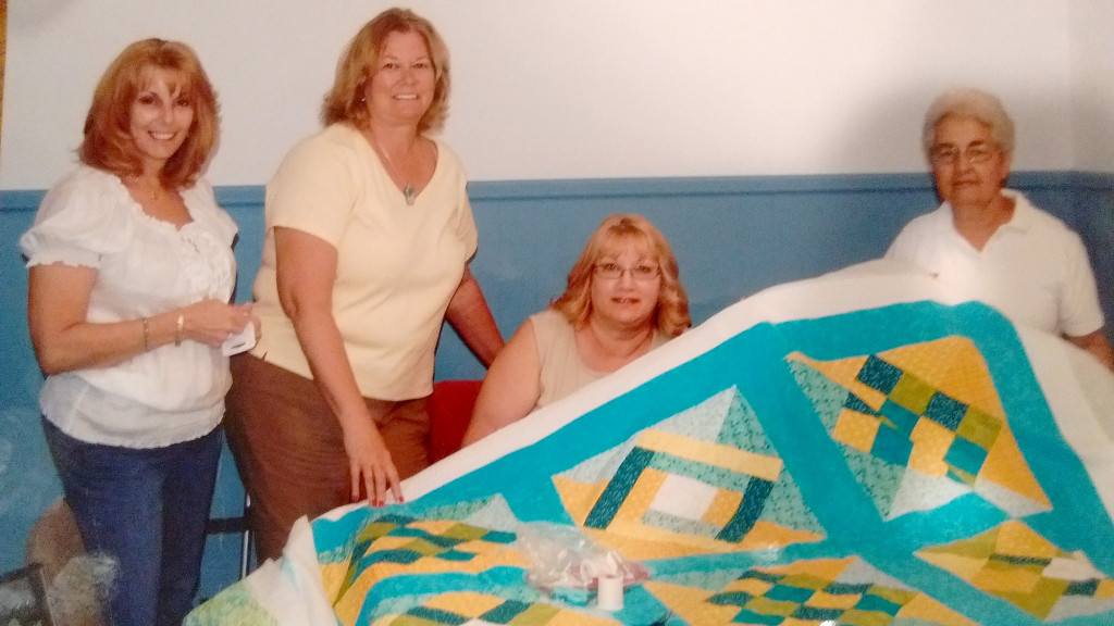 (above l-r) Auxiliary members Karen Mormack, Judy Doran, Kathy Switek and Florence Roberts showing one of the quilts made by them.