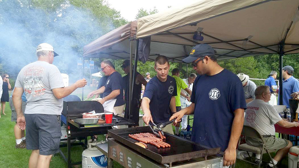(above) Neil Vaish (front right) of the Stirling Fire Department grills hot dogs and hamburgers provided free of charge to attendees. 