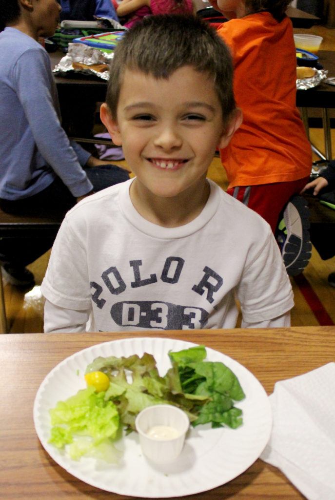 (above) Mt. Horeb first grader Aydin Cakirdas is all smiles as he samples a salad fresh from his school garden.